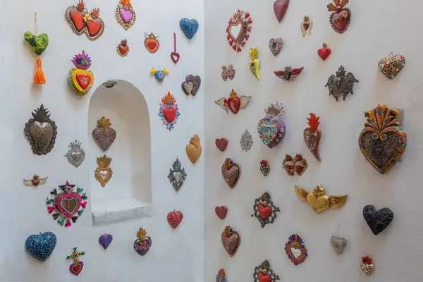 stock image Composition of decorative Mexican glass and metal hearts on a white wall