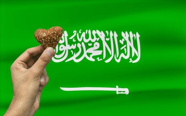 Suudi Arabistan bayrağının arka planında kalp şeklinde geleneksel Orta Doğu kibbeleri sergilenmektedir.