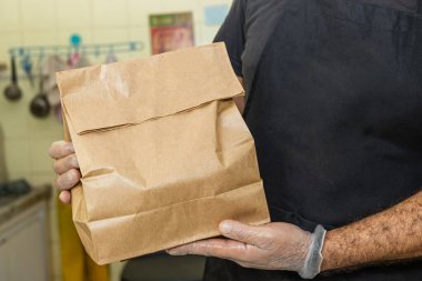 Mutfak çalışanı paket servis siparişini kağıt torba ve yemek dağıtımı ile gösteriyor.
