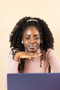 Pembe elbiseli şirin Afrikalı kız kameraya bakıp elini yüzüne koyuyor.