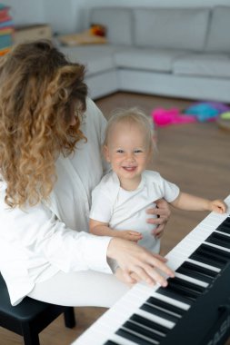 Küçük kız piyanoda annesinin eline oturur ve çalmayı öğrenir. Müzik sınıfı