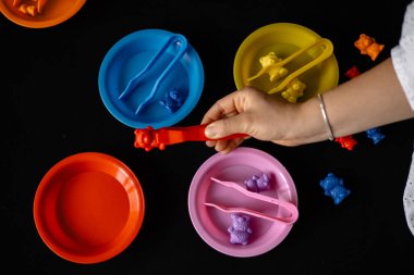 Cımbız ve küçük oyuncaklar kullanan çocuklar için motor becerilerinin geliştirilmesi. siyah arkaplan