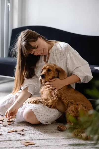 Cocker spaniel köpeği evde yerde sahibine sarılıp oynuyor. Sevimli evcil hayvan, en iyi arkadaşlar.