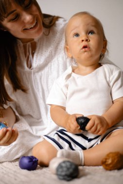 Bir anaokulu öğretmeni ve bir kız çocuğu çeşitli dolgularla özel topların yardımıyla iyi motor becerileri geliştiriyorlar..