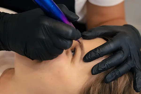 Dövme salonunda sürekli makyaj yapan genç bir kadın, yakın plan.