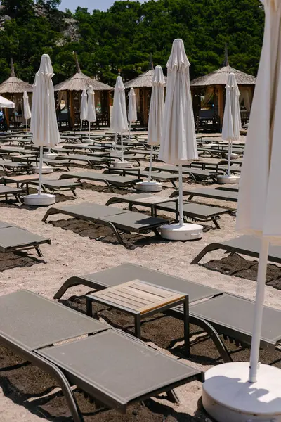 Güneşli şezlongları, masaları ve beyaz şemsiyeleri olan güzel boş kumsal, yaz.