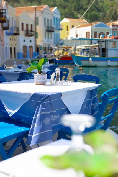 Geleneksel Yunan restoranındaki sandalye ve masalar, lacivert renkler, deniz ve tekneler, insan yok.