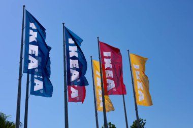 Antalya, Türkiye - 19 Haziran 2024: Mavi gökyüzüne karşı dalgalanan renkli IKEA bayrakları