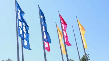Antalya, Türkiye - 19 Haziran 2024: Mavi gökyüzüne karşı dalgalanan renkli IKEA bayraklarının videosu