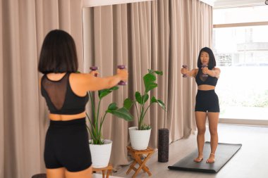Çekici Asyalı kadın spor eğitmeni aynanın önünde duruyor ve pilates ve yoga stüdyosundaki aptallarla spor yapıyor..