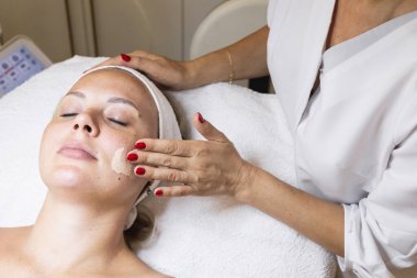 Kozmetoloji prosedürü, doktorun güzellik salonundaki masaj hareketleriyle cilt kremi sürmesi. Ellerinizi ve yüzünüzü kapatın. Doğal sorunlu cilt. Klinik ya da güzellik salonu
