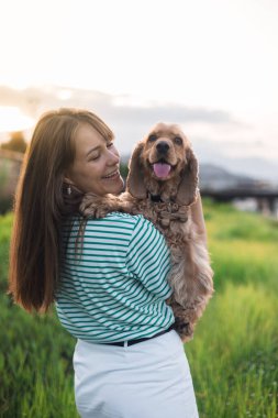 Genç ve güzel bir kadın ve cocker köpeğinin portresi, halk parkında yaz günbatımı.