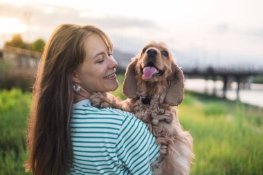 Genç ve güzel bir kadın ve cocker köpeğinin portresi, halk parkında yaz günbatımı.