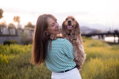 Genç ve güzel bir kadın ve cocker köpeğinin portresi, halk parkında yaz günbatımı.