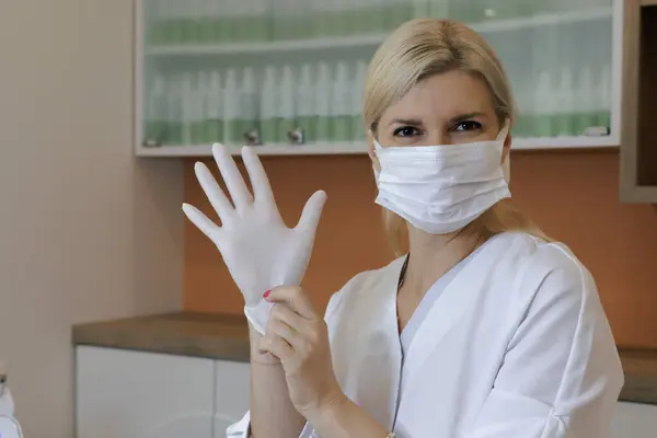 Kozmetik atölyesindeki güzellik dolabının manzarası. Ameliyattan önce beyaz eldiven takan doktor kozmetik uzmanı portresi.