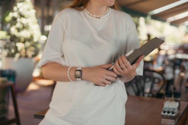 Restoranda dizüstü bilgisayarlı ve akıllı telefonlu kızıl saçlı iş kadını. Sıradan giyinmiş. Masaların bulanık arka planına sahip bir kafede dikiliyorum. çevrimiçi çalışma, serbest çalışma ve öğrenim kavramı