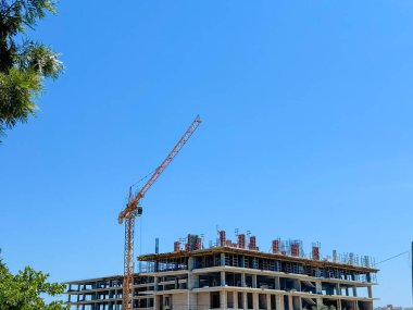 Vinç ve inşaat etkinliği kaldırılıyor. İnşaat alanı. Yeni bina ya da evin inşaatı. Güneşli yaz günü ve mavi gökyüzü... Uzayı kopyala Yüksek kalite fotoğraf
