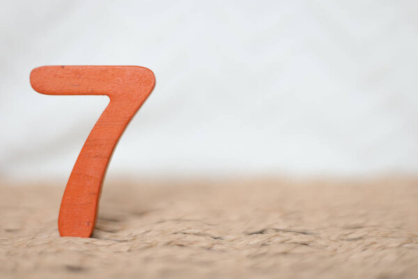 Крупный план деревянная оранжевая цифра семь на белом размытом фоне, праздничная дата, юбилей, юбилейная открытка с копией места для текста