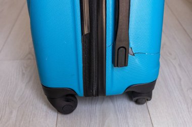 Hasarlı mavi seyahat valizi, kırık bavul, kırık bavul tekerleği. 