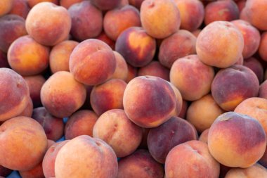 Marketteki bir tezgahta sulu taze şeftali, yaz mevsimi sağlıklı meyveler, bulanık arka plan