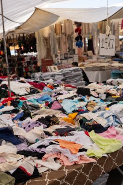 03.08.2024 Antalya, Türkiye - Pazar. Türkçe tezgahında çeşitli sahte tasarımcı kıyafetleri var. Giysiler üst üste yatar. Ucuz fiyatlar ve moda markalarına alternatifler. Eski satışlar