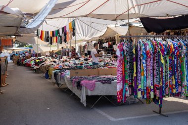 Antalya, Türkiye - 3 Ağustos 2024 - Pazar. Türkçe tezgahında çeşitli sahte tasarımcı kıyafetleri var. Giysiler üst üste yatar. Ucuz fiyatlar ve moda markalarına alternatifler. Eski satışlar