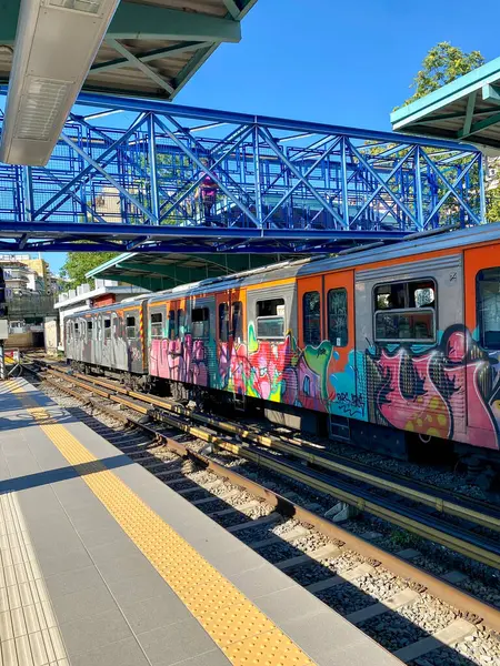 stock image Athens, Greece - August 2021: Metro station in Athens, train painted full of colorful graffiti leaving the station, ground crossing