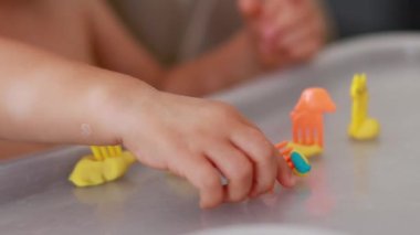 Bebek el oyunları masasında renkli mavi ve sarı plastikler ve hayvanlar, çocuklarda iyi motor becerilerin ve hayal gücünün gelişimi, yürümeye başlayan oyunlar ve boş zamanlarında