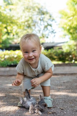Sevimli sarışın kızın portresi. Halk parkında sokak kedilerini oynatıp kucaklıyor. Evsiz hayvanlara sevgi ve ilgi. Çocukların dokunaklı resimleri kedileri sever. Tüylü arkadaşlar ve hayvan bakımı