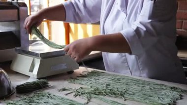Kadın el yapımı makarna hazırlıyor. Makarna yapmak için hamurla çalışan kadın elleri. Şef makarna yapmak için yeşil hamur kurusıkı yapıyor. Beyaz ceketli şef restoran mutfağında yemek hazırlıyor. Kadın