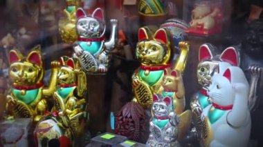 Vitrinde sağ pençesi olan bir sürü kediden hatıra. Maneki-neko ya da işaret eden kedi, genellikle sahibine iyi şans getirdiğine inanılan yaygın bir Japon biblosudur. seramik ve plastik