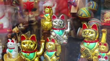 Vitrinde sağ pençesi olan bir sürü kediden hatıra. Maneki-neko ya da işaret eden kedi, genellikle sahibine iyi şans getirdiğine inanılan yaygın bir Japon biblosudur. seramik ve plastik