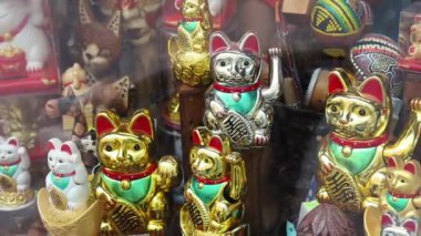 Vitrinde sağ pençesi olan bir sürü kediden hatıra. Maneki-neko ya da işaret eden kedi, genellikle sahibine iyi şans getirdiğine inanılan yaygın bir Japon biblosudur. seramik ve plastik