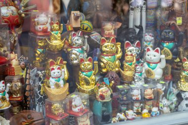 Vitrinde sağ pençesi olan bir sürü kediden hatıra. Maneki-neko ya da işaret eden kedi, genellikle sahibine iyi şans getirdiğine inanılan yaygın bir Japon biblosudur. seramik ve plastik