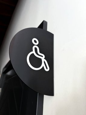 A clearly designed restroom sign features a symbol representing accessibility, specifically intended for individuals with disabilities. This sign is displayed prominently on a wall, ensuring that it clipart