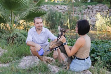 Bir köpekle yürüyen mutlu bir çift, parkta sarılıp öpüşüyor yaz günbatımında, erkek ve kadın portresi, birlikte kolay ve keyifli bir zaman, büyük bir yaş ile ilişki kavramı