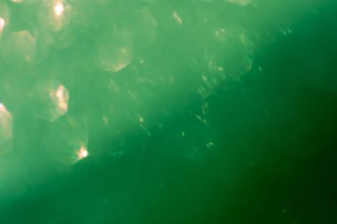 Soyut parıltılı ışıklar koyu yeşil arkaplanlı, odaklanmamış, bokeh. Noel ya da Yeni Yıl Festivali ışıl ışıl arka plan, kış tatili kartı kavramı