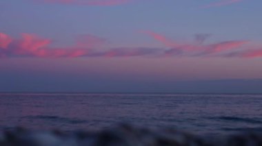 Ufuk boyunca pembe renkler saçan çarpıcı bir günbatımına tanık olun. Yumuşak dalgalar kıyıya doğru süzülürken barışçıl bir atmosfer yaratıyor. Alacakaranlıkta güzelliği tecrübe etmek. Kısmen bulanık arkaplan