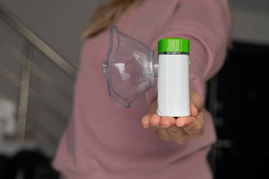 Close-up of female hands holds oxygen mask of nebulizer with steam, medical equipment for pneumonia, covid, sars and bronchitis treatment. Inhaler, respiratory pulmonary disease, child allergy. clipart