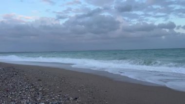 Akşamları kumlu bir plajda dalgalar kıyıya vurur, gökyüzünde bulutlar yükselir. Sakin atmosfer, gün batımına dönerken dinlenmeyi ve düşünmeyi davet eder. Türkiye 'de kış