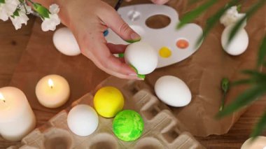 Eğlenceli ve renkli yumurta dekorasyonu aktivitesi. Parlak boyalar beyaz yumurtalarda kullanılıyor. Mumlar ise yaratıcı süreci geliştirmek için rahat bir atmosfer sağlıyor. Paskalyaya hazırlanıyor