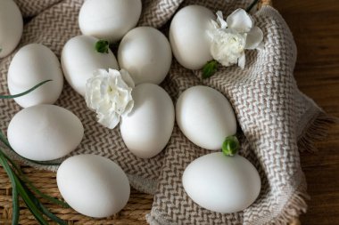 A selection of white eggs arranged on a textured cloth within a handcrafted basket, symbolizing Easter festivities during the vibrant spring season, showcasing themes of renewal and tradition. clipart