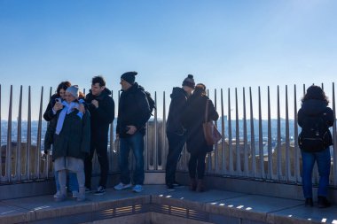 Paris, Fransa - 12 Ocak 2025: Arc de Triomphe ve izleme platformu. Turistler gözlem güvertesinde toplanıyor, bazıları selfie çekiyor ve diğerleri açık mavi gökyüzünün altında büyüleyici şehir manzarasına hayran.