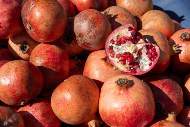 Parlak kırmızı nar, parlak derilerini ve canlı renklerini sergileyerek bir tezgahı doldurur. Kesilmiş bir meyve sulu tohumları ortaya çıkarır, sıcak sonbahar ışığında müşterileri cezbeder..