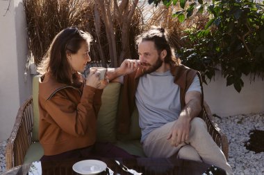 Birbirine aşık çiftler beyaz kahveyi ellerinde tutarlar ve birbirlerine şefkatle bakarlar. Genç bir adam ve bir kadın bir kafe 'nin yaz terasında oturuyorlar ve sıcak günün ve güneşin tadını çıkarıyorlar..