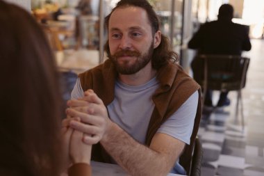 Genç çift rahat bir kafede el ele tutuşup birbirlerine dokunarak birbirlerine dokunuyorlar. Gülüşleri romantik atmosferi gösteriyor. Gözlerinde aşk olan kadına bakan bir adam.. 