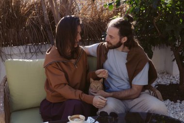 Genç evli bir çift bahçede terasta oturuyor, birbirlerine sarılıyorlar, bir hayvan barınağından gelen kızıl kızıl kediyi okşuyorlar. Yeni tüylü bir aile üyesi, hayvanlara karşı sevgi, nezaket, evcil hayvan dostu