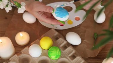 Eğlenceli ve renkli yumurta dekorasyonu aktivitesi. Parlak boyalar beyaz yumurtalarda kullanılıyor. Mumlar ise yaratıcı süreci geliştirmek için rahat bir atmosfer sağlıyor. Paskalyaya hazırlanıyor