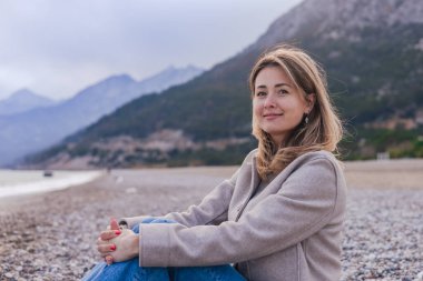 Güzel genç bir kadın çakıl taşı kaplı plajda oturuyor. Gülümsüyor ve hayal kuruyor. Kadın, denizin dingin güzelliğinin ve çevreleyen dağlık manzaranın tadını çıkarıyor. Türkiye 'nin Antalya kentinde kış