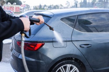 Aydınlık bir günde siyah bir araba bir benzin istasyonunda yıkanmaktadır. Su ve sabun köpüğü aracın arkasını kaplıyor. Temiz bir bitiş için durulanıyor..